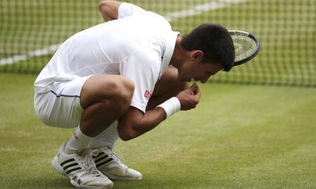 O tenista sérvio Novak Djokovic comemora seu título em Wimbledon em 2015 comendo grama