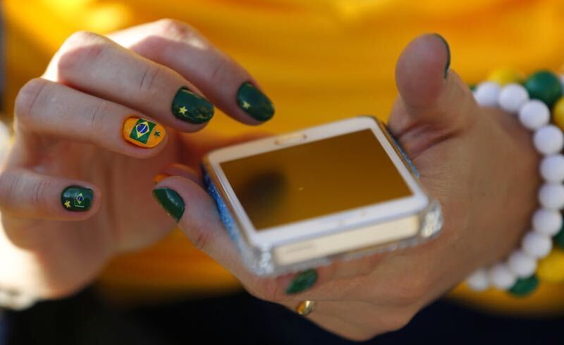 Torcedora brasileira segura um celular: apostas com Pix estão em alta